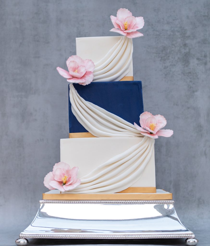 3 tier, blue and white cake. with swags and handmade peonies